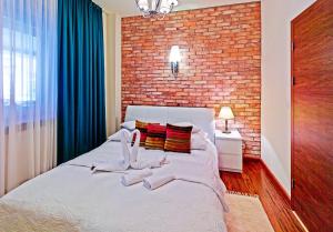 a bedroom with a white bed with a brick wall at Hotel Wenecki in Częstochowa