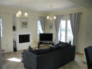 un salon avec un canapé noir et une télévision dans l'établissement Villa bel fiore, Brand new Great View, à Katouna