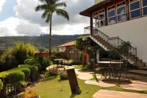 ein Haus mit einem Tisch und Stühlen und einer Palme in der Unterkunft San Diego Suítes Hotel Quadrado in Santa Bárbara