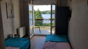 a room with two beds and a door to a balcony at RIVA Ośrodek Wypoczynkowy in Więcbork