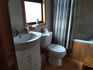 un bagno con lavandino, water e finestra di Refugio Altazor a Las Trancas