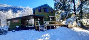 una casa verde con un ponte nella neve di Refugio Altazor a Las Trancas