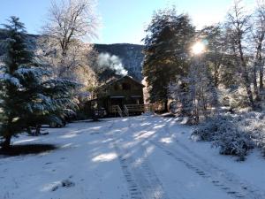 a snow covered road in front of a log cabin at Refugio Altazor in Las Trancas