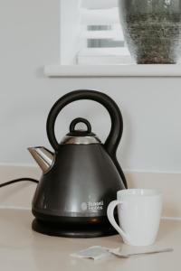 a black tea kettle and a cup on a counter at 2 The Mews, Upper Bath Street in Cheltenham