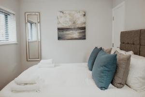 
a white bed with a white comforter and pillows at 2 The Mews, Upper Bath Street in Cheltenham
