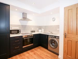 a kitchen with black cabinets and a washing machine at The Keepers Cottage at The Institute Executive Apartments in Keith