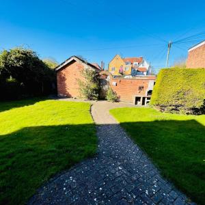 a walkway in a grassy yard with a house and a windmill at Lyndene Holiday Apartments in Skegness