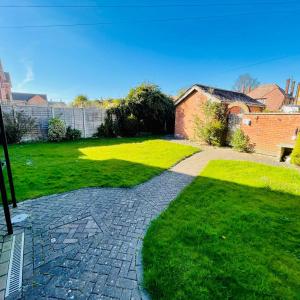 a garden with a brick house and a walkway at Lyndene Holiday Apartments in Skegness