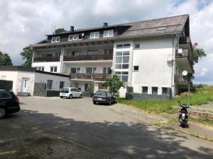ein großes weißes Gebäude mit davor geparkten Autos in der Unterkunft Aventur Studio 212 Am Rotharrsteig in Medebach