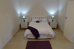 a bedroom with a white bed with two night stands at Lovely 2-bedroom apartment with free parking on premises in Jeffreys Bay