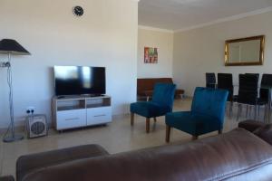a living room with a couch and chairs and a flat screen tv at Lovely 2-bedroom apartment with free parking on premises in Jeffreys Bay
