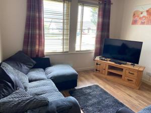 sala de estar con sofá y TV de pantalla plana en Welcoming House in Portree Isle of Sky Scotland, en Portree