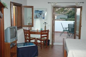 a living room with a television and a table with chairs at Punto de Vista B&B Makari in San Vito lo Capo