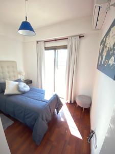 a bedroom with a blue bed and a large window at Patio San Ignacio in San Juan