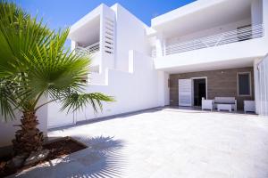 a white house with a palm tree in front of it at Donnosanto Residence Pantanagianni in Torre Santa Sabina