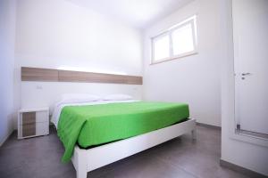 sypialnia z łóżkiem z zielonym kocem w obiekcie Donnosanto Residence Pantanagianni w mieście Torre Santa Sabina