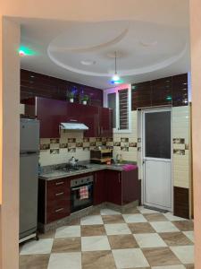 a kitchen with purple cabinets and a checkered floor at Appartement Mus saidia 1 in Saidia 