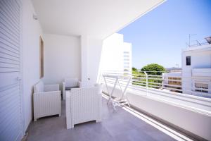 a balcony with white chairs and a large window at Donnosanto Residence Pantanagianni in Torre Santa Sabina