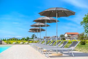 a row of chairs with umbrellas next to a pool at Terra Fina in Savio di Ravenna