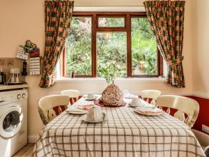 a kitchen with a table and a window and a washing machine at Wood End in Dalbeattie