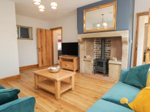 a living room with a fireplace and a blue couch at Carrock Cottage in Dalston