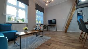a living room with a blue couch and a table at Antresola - Apartamenty Parkowe in Gniezno +7 photos