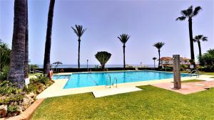 una piscina con palmeras en un complejo en Los Flamingos - Front Line Apartment La Cala, en Mijas Costa