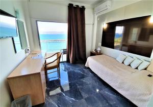 sypialnia z biurkiem i łóżkiem z widokiem na ocean w obiekcie Porto Evia Boutique Hotel w mieście Amarynthos