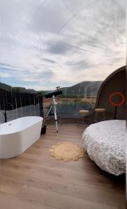 Burbuja AntiSaturno - Glamping Alto Tajo في Ablanque: غرفة نوم مع حوض استحمام وكاميرا