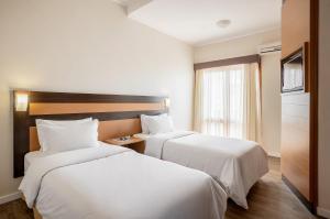 a hotel room with two beds and a window at Piazza Navona Porto Alegre by Intercity in Porto Alegre