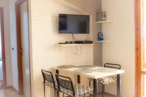 una camera con tavolo, sedie e TV a parete di Calabria Dream Holiday Home a Scalea