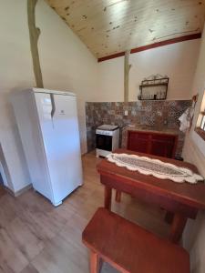 a kitchen with a white refrigerator and a stove at Chalé Recanto das palmeiras in São Thomé das Letras