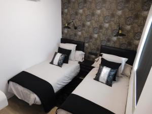 Habitación pequeña con 2 camas y almohadas blancas y negras. en HOTEL TERRA GALEGA MEIGA, en Monforte de Lemos