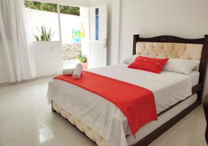 a bedroom with a large bed with a red blanket at Hotel Manakin Tayrona in El Zaino