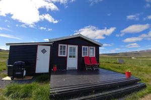 a tiny house with two red chairs on a deck at Cosy Cottage-Álfabakki-with hot tub in Stóri-Bakki