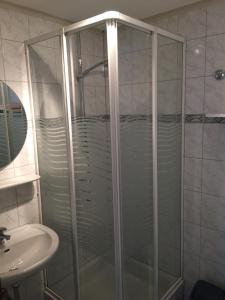 una ducha con una puerta de cristal junto a un lavabo en Haus Serena en Sonnenalpe Nassfeld