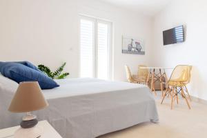 1 dormitorio blanco con 1 cama con almohadas y sillas azules en Case Vacanza Apollo en Torre San Giovanni Ugento