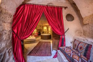 a room with red curtains in a stone building at Cappadocia Eagle Cave Inn in Nevsehir