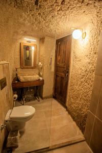 a stone bathroom with a toilet and a mirror at Cappadocia Eagle Cave Inn in Nevsehir