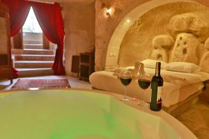 a bathroom with a tub with two glasses of wine at Cappadocia Eagle Cave Inn in Nevsehir