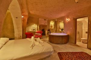 Cappadocia Eagle Cave Inn في نوشهر: غرفة نوم بسرير كبير وحوض استحمام