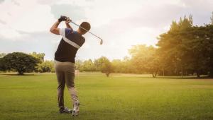 a man swinging a golf club in a park at Thunderbird Motel Hillsboro in Hillsboro
