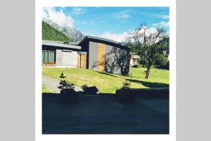 a house on a grassy field next to a building at L'edelweis in Le Bourg-dʼOisans