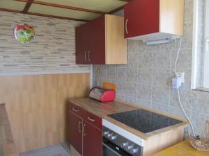 uma pequena cozinha com armários vermelhos e um lavatório em zum Wiesengrund im Oderbruch em Altglietzen