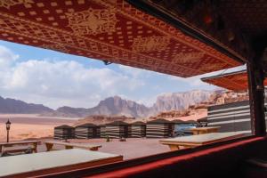 einen Blick auf die Wüste von einem Gebäude mit Tischen und Bänken in der Unterkunft Wadi Rum Desert Home in Wadi Rum