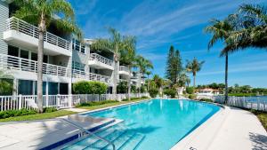 a swimming pool in front of a building with palm trees at Harbor Villa Club 206 in Longboat Key