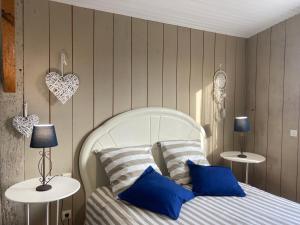 1 dormitorio con cama blanca y almohadas azules en La Casa Cantarana, en Le Teich