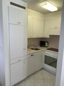 a kitchen with white cabinets and a sink at Schönegg Studio in Riederalp