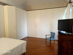 Schlafzimmer mit einem Bett, einem TV und einem Stuhl in der Unterkunft Villa D'Albertis in Crevari