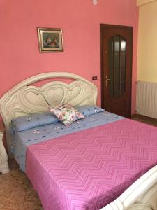um quarto cor-de-rosa com uma cama branca e lençóis cor-de-rosa em VILLA FELICE em Loano